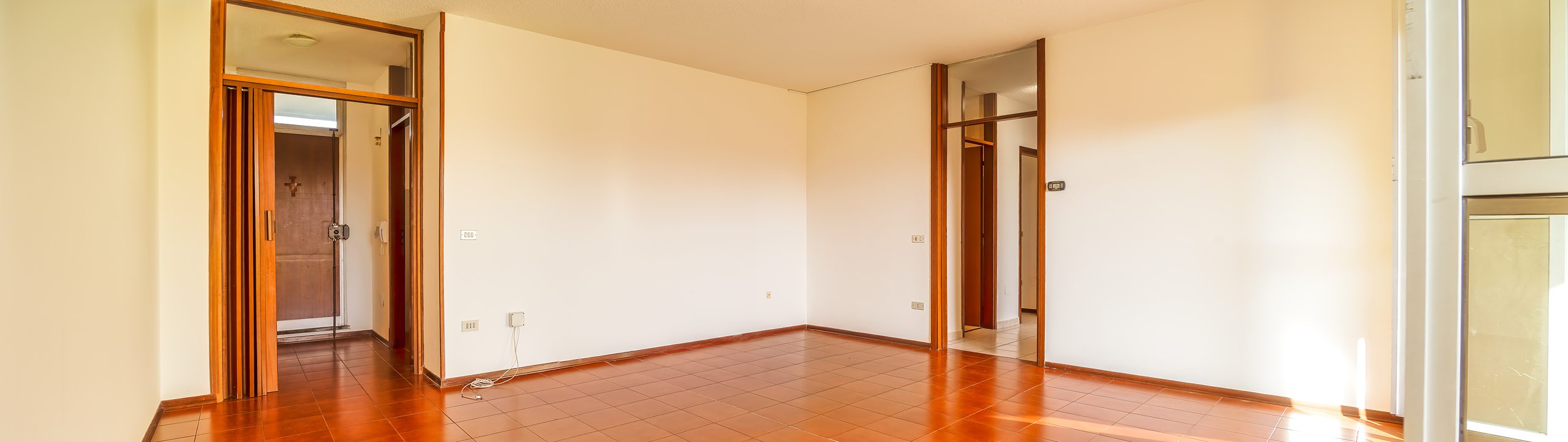 Vista panoramica del salone con le due porte-finestre aperte sul balcone