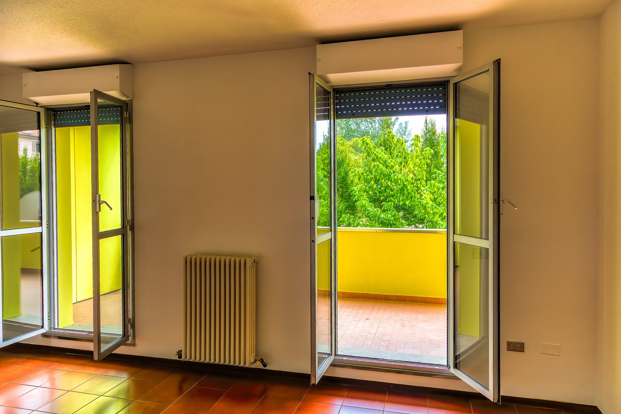 Salone con le porte-finestre aperte sul balcone e sul Parco della Pace
